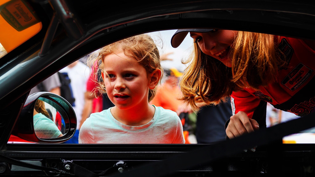Aurora Straus shows a young girl her race car. Photo credit: Wes Duenkel, used with permission